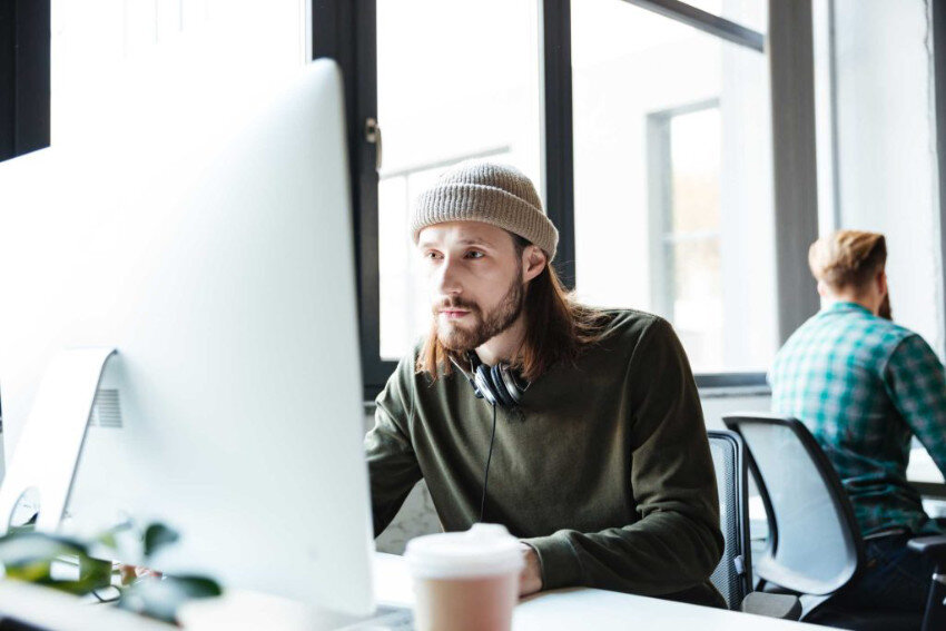 Young man sitting at the desk at the office and working on the computer